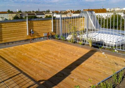 Dachterrasse mit Holzbeplankung und angrenzenden Pflanzflächen