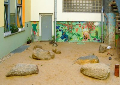 Schulhof mit Sandfläche und großen Steinen